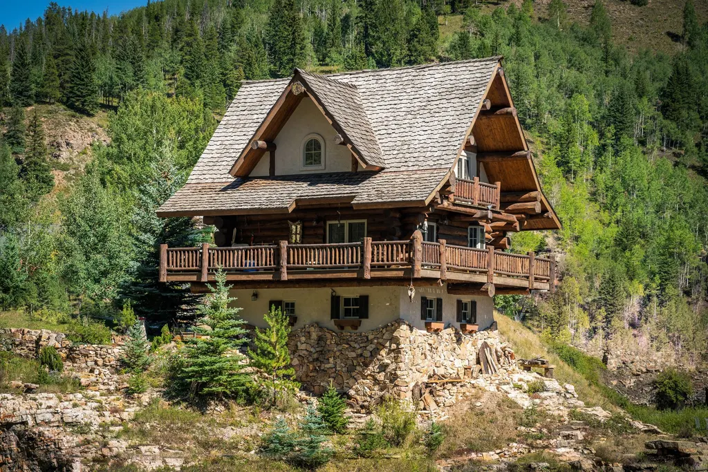 A rustic two-story log home with a wraparound deck built into a rocky hillside near Durango, Colorado.