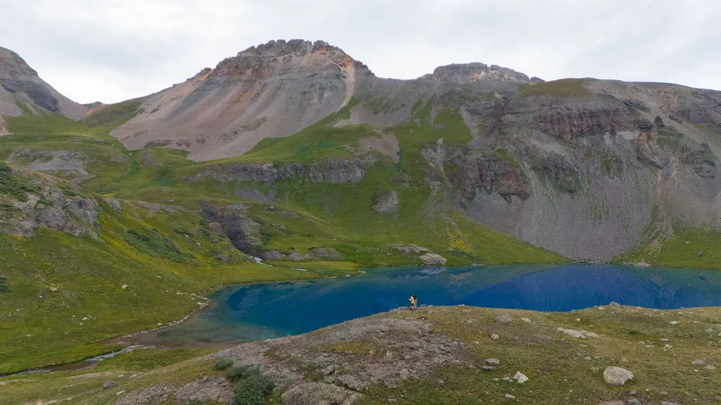 A lone hiker beside a vivid alpine lake in the San Juan Mountains near Durango, Colorado
